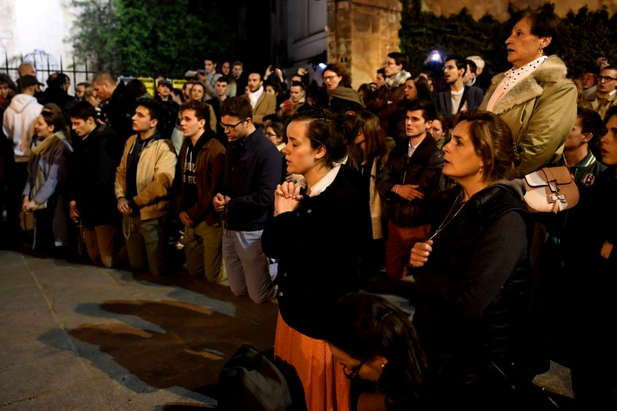 i parigini pregano davanti alla cattedrale che brucia
